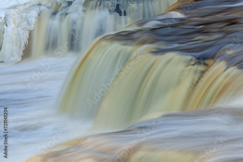 Winter landscape of Lower Tahquamenon Falls framed by ice and captured with motion blur, Michigan's Upper Peninsula, USA