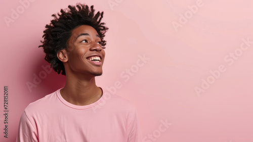 Cheerful young man in pink shirt looking upwards photo