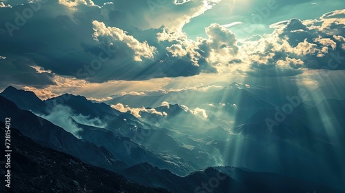 This is a breathtaking view of mountain ranges basking in a dramatic light. The sunlight pierces through the cloud cover in bold rays, illuminating patches of the rugged terrain below. The juxtapositi photo