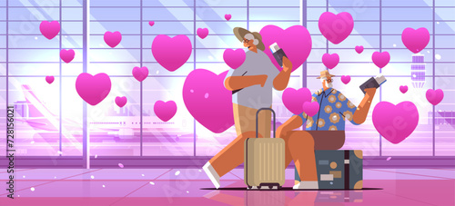 senior couple of tourists grandparents in love with luggage holding passports and tickets at airport with pink hearts valentines day celebration