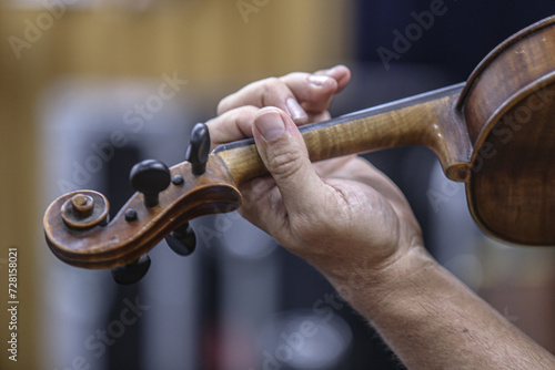 man playing violin, view of hand holding violin, violinist playing at concert
