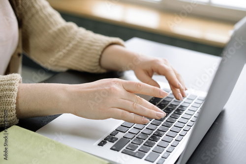Close up of female hands typing on modern laptop keyboard making notes writing on device.