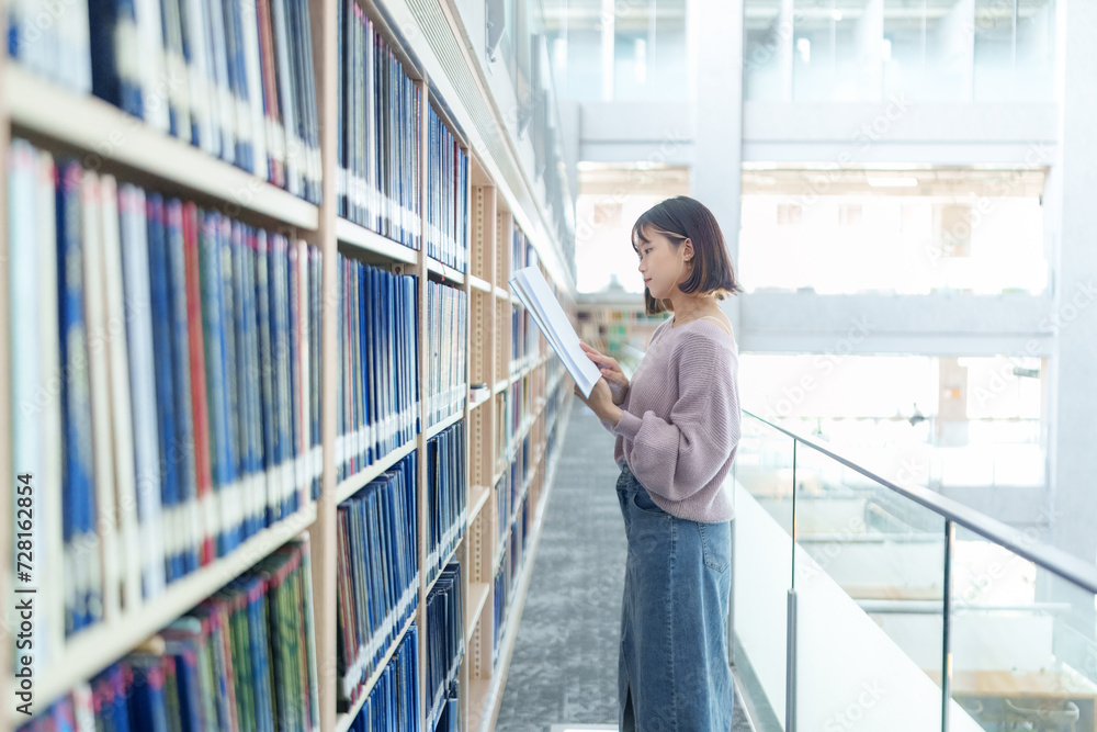 Fototapeta premium 台湾台北市文山区の大学にある美しい図書館で過ごす20歳の台湾人女性の大学生のスローモーション映像 Slow-motion video of a 20-year-old Taiwanese female college student spending time in a beautiful library at a university in Wenshan District, Taipei Ci