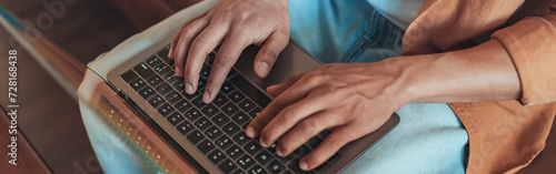 Close up of man freelancer working on laptop while sitting on sofa in cozy coworking