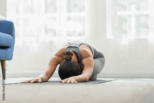 Asian woman wearing green sportwear doing Yoga exercise,Yoga Child’s pose or Balasana,Calm of healthy young woman breathing and meditation with yoga at home,Exercise for wellness life