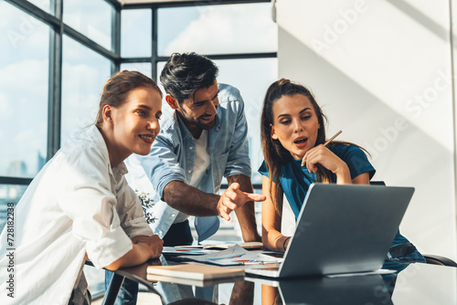 Group of diverse profession business people pointing at laptop displayed idea. Portrait of business team show marketing strategy present by laptop with statistic document scatter on table. Tracery.