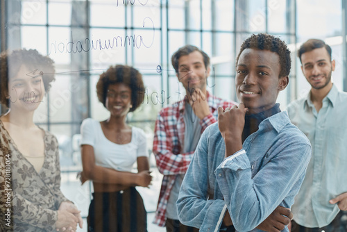 a team of young designers sticking notes on glass in a modern office © Katsiaryna