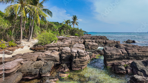 Tropical beach with rocky formations, palm trees, and clear blue water, ideal for travel and vacation concepts © fotogurmespb
