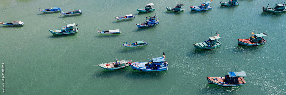 Aerial view of multiple colorful fishing boats scattered on calm sea water