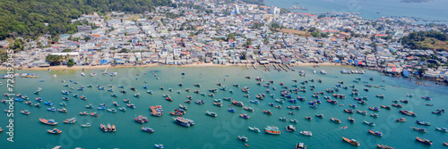 Aerial view of a bustling coastal town with numerous boats anchored in a calm bay photo