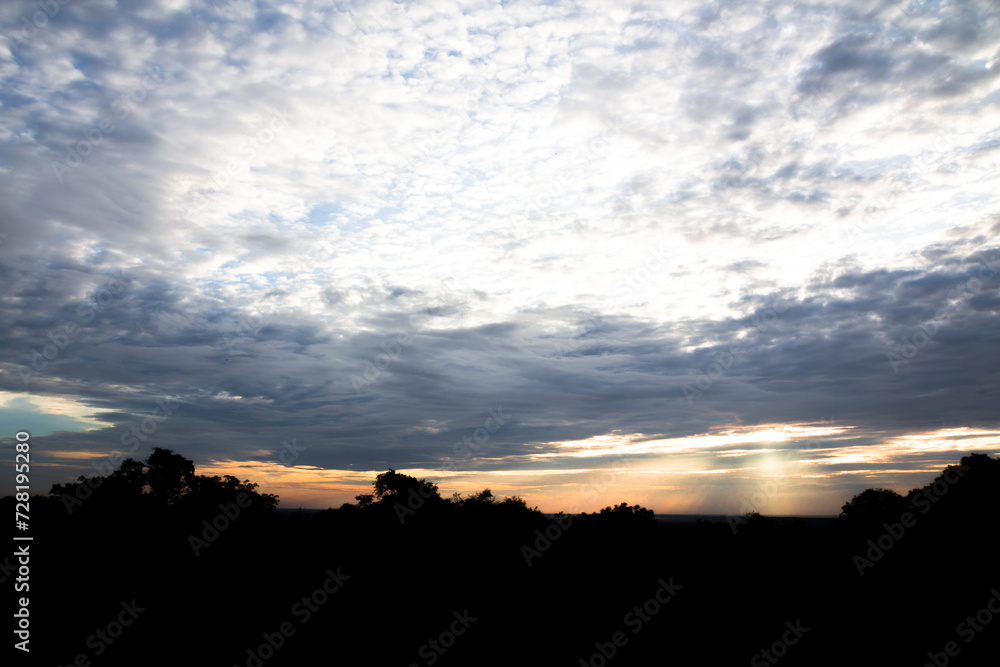 Naklejka premium Panoramic cloudscape with the sun rays radiating from behind the cloud.Phnom Bakheng sunset view Angkor Wat, Siem Reap, Cambodia