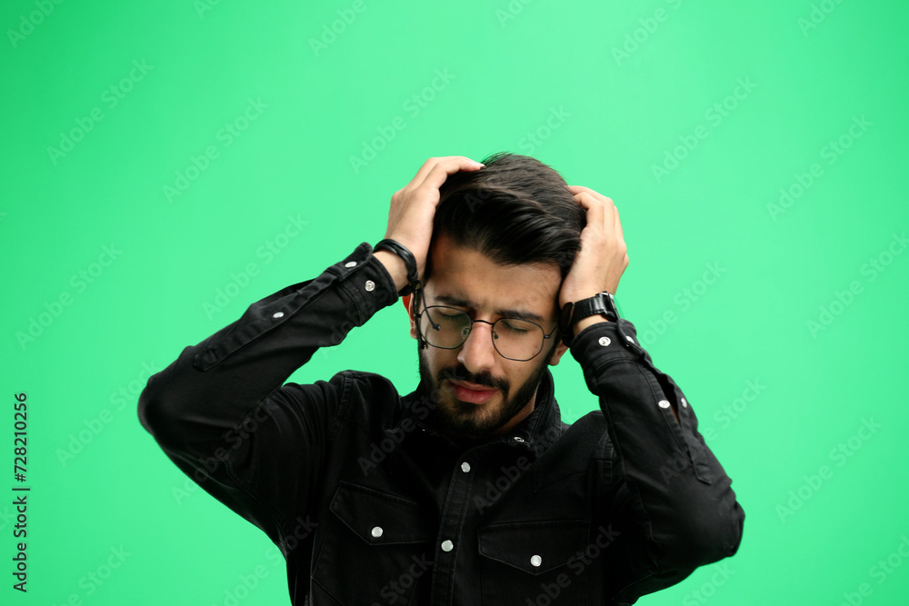 Man, on a green background in close-up, headache