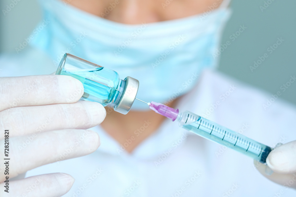 doctor's hand holds a syringe and a blue vaccine bottle at the hospital. Health and medical concepts. doctor's hand holds a syringe and a blue vaccine bottle at the hospital. Health and medical concepts.