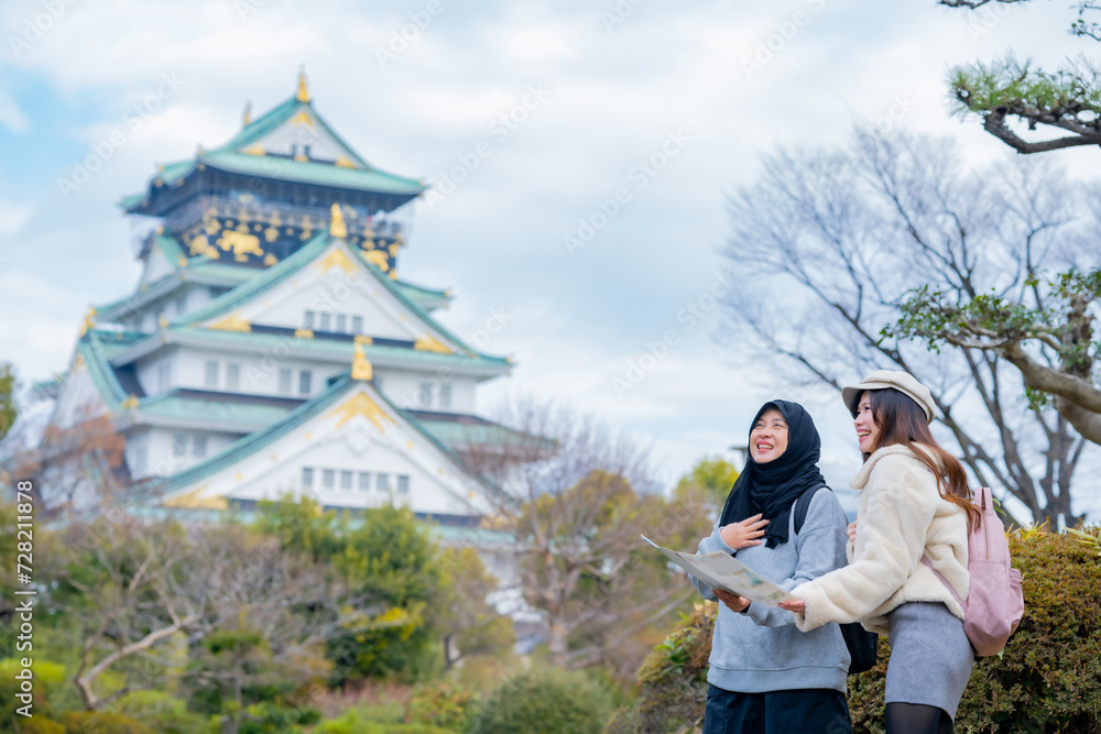 Obraz premium Travel, muslim travel, woman girl tourist Two Asian friends but different religions walking at Osaka Castle, Osaka Castle is one of the most famous landmarks in Japan and Osaka, holiday lifestyle.
