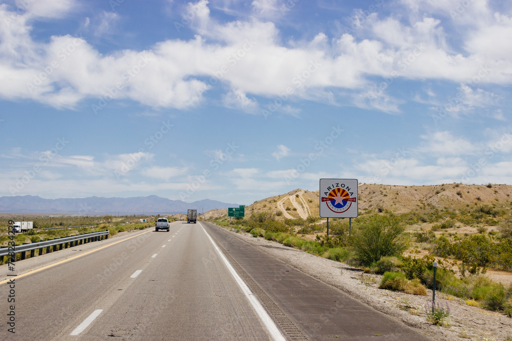 Beautiful blue sky with fluffy clouds over the highway on a spring day. Arizona sign. Scenic road in Arizona, USA on a sunny summer day. Arizona, USA - 17 April 2020