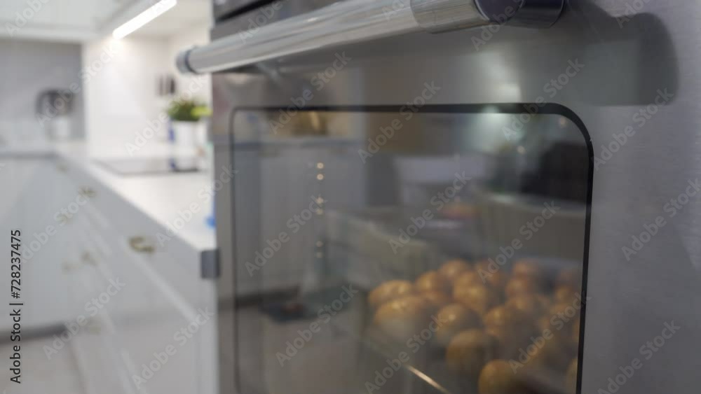 white modern kitchen, baking in the oven. Baked jacket potatoes are cooking in the oven white modern kitchen, baking in the oven. Baked jacket potatoes are cooking in the oven