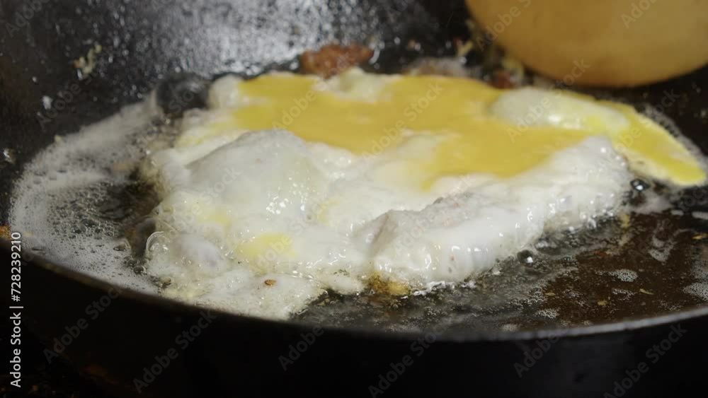 Closeup: Egg with broken yolk fries in butter in hot cast iron skillet Closeup: Egg with broken yolk fries in butter in hot cast iron skillet