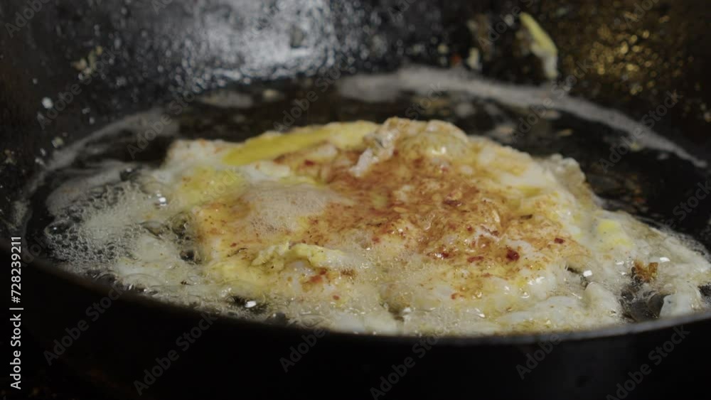 close-up view: Tasty egg sizzles and bubbles in hot butter frying pan close-up view: Tasty egg sizzles and bubbles in hot butter frying pan