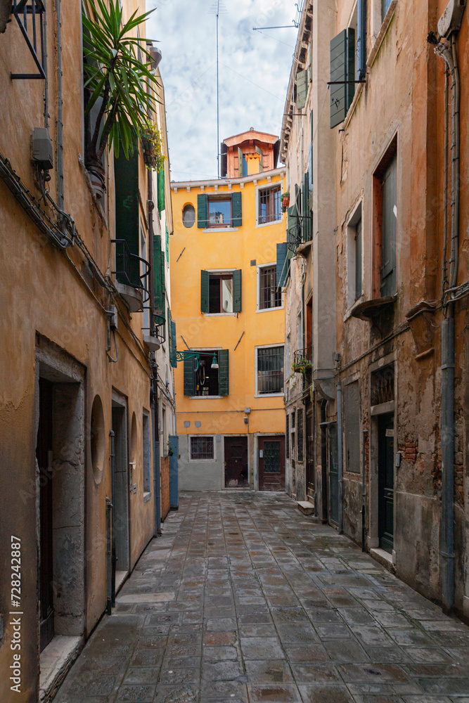 Typical narrow street with historical houses in Venice. Narrow pedestrian streets of Venice between the channels. Some quiet places almost without people. Typical narrow street with historical houses in Venice. Narrow pedestrian streets of Venice between the channels. Some quiet places almost without people.