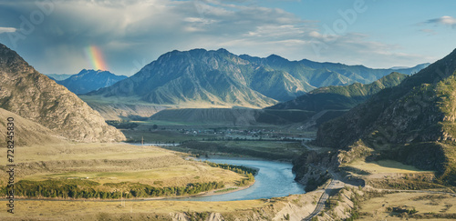 Mountain valley in contrasting evening light, rainbow