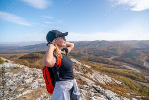 woman on mountain peak looking in beautiful mountain valley in autumn. Landscape with sporty young woman, blu sky in fall. Hiking. Nature