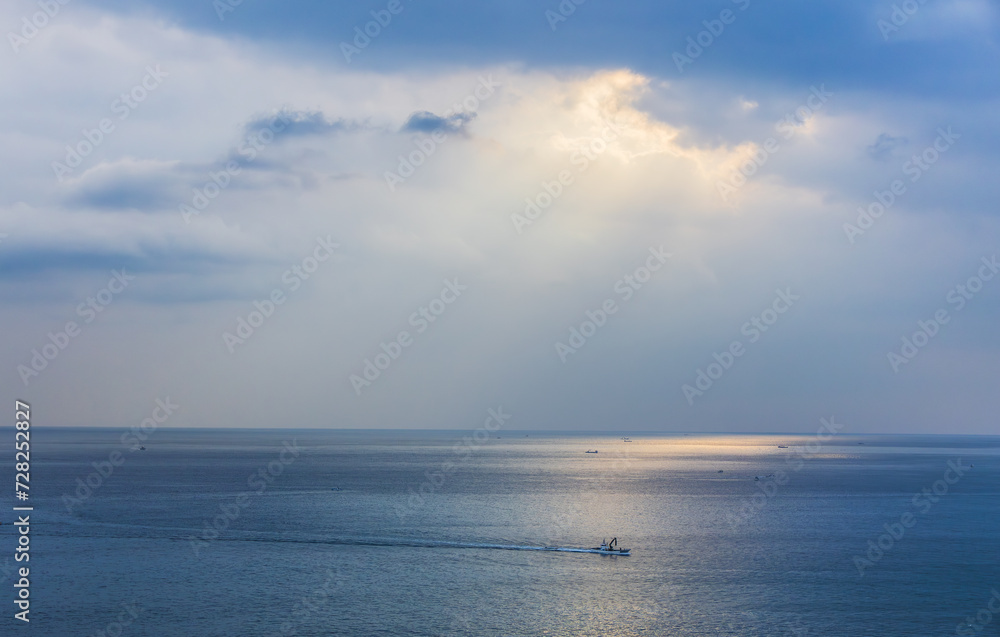 Sunlight pouring through the clouds reflects on the surface of the sea. Morning sunrise scenery on the sea