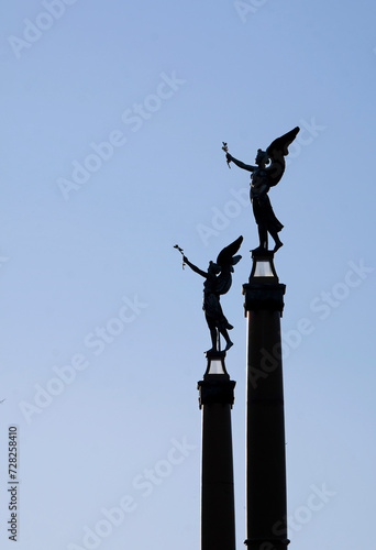Two angel statues with wings against the blue evening sky