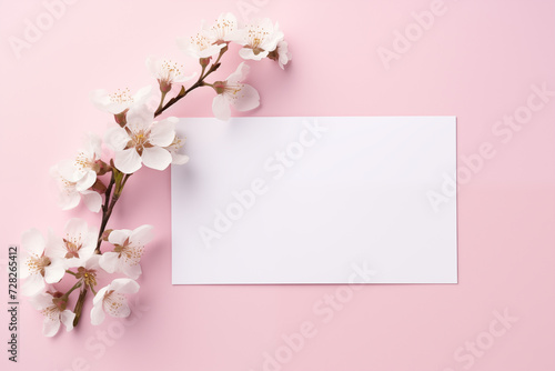 White Paper Sheet Card Mockup with Flowers on Pastel Pink Background. Empty Card Mockup with Copy Space