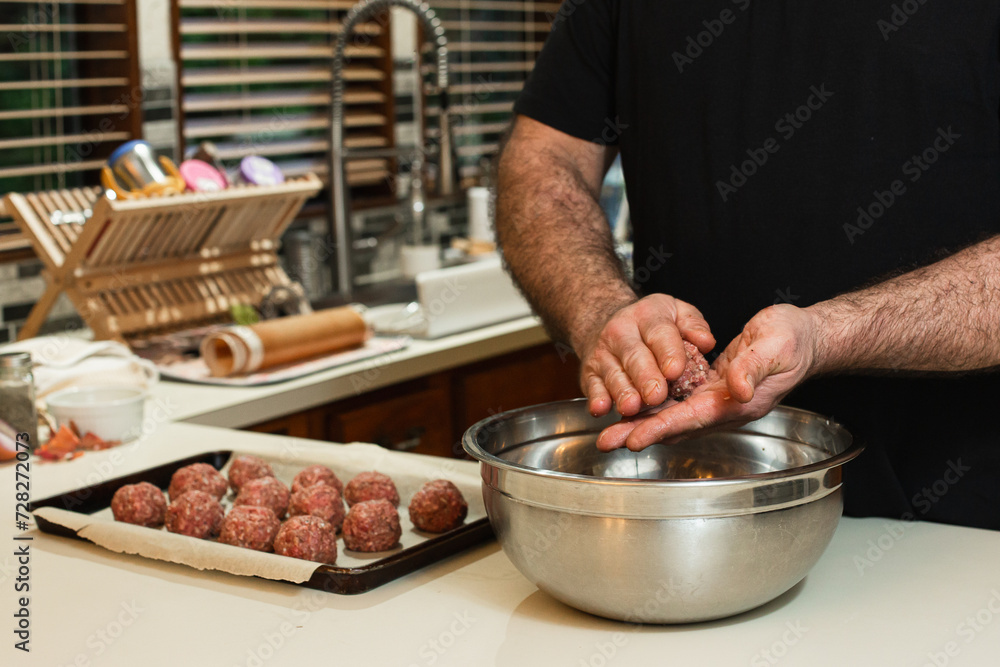 Male chef shaping meatballs in a home kitchen
