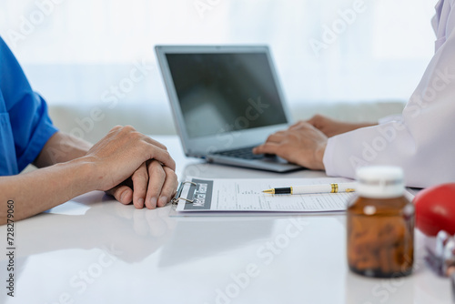 Provide medical consultation Doctor talking with patient in clinic office Focus on the hand and stethoscope Doctor and patient sit and talk with patient about medication. At the table by the window