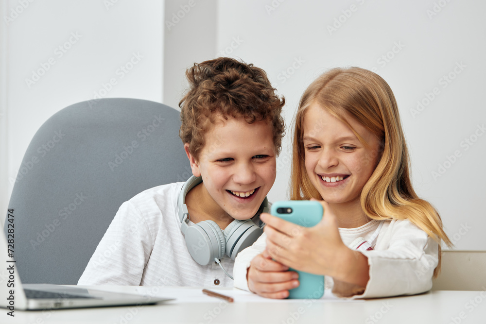 Happy children studying together at home using laptops and headphones The boy and girl are engaged in online elearning, sitting on a cozy couch in the living room Their focus and concentration reflect Happy children studying together at home using laptops and headphones The boy and girl are engaged in online elearning, sitting on a cozy couch in the living room Their focus and concentration reflect