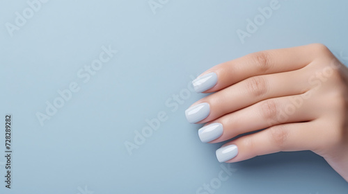 Glamour woman hand with blue nail polish on her fingernails. Pastel color nail manicure with gel polish at luxury beauty salon. Nail art and design. Female hand model. French manicure.