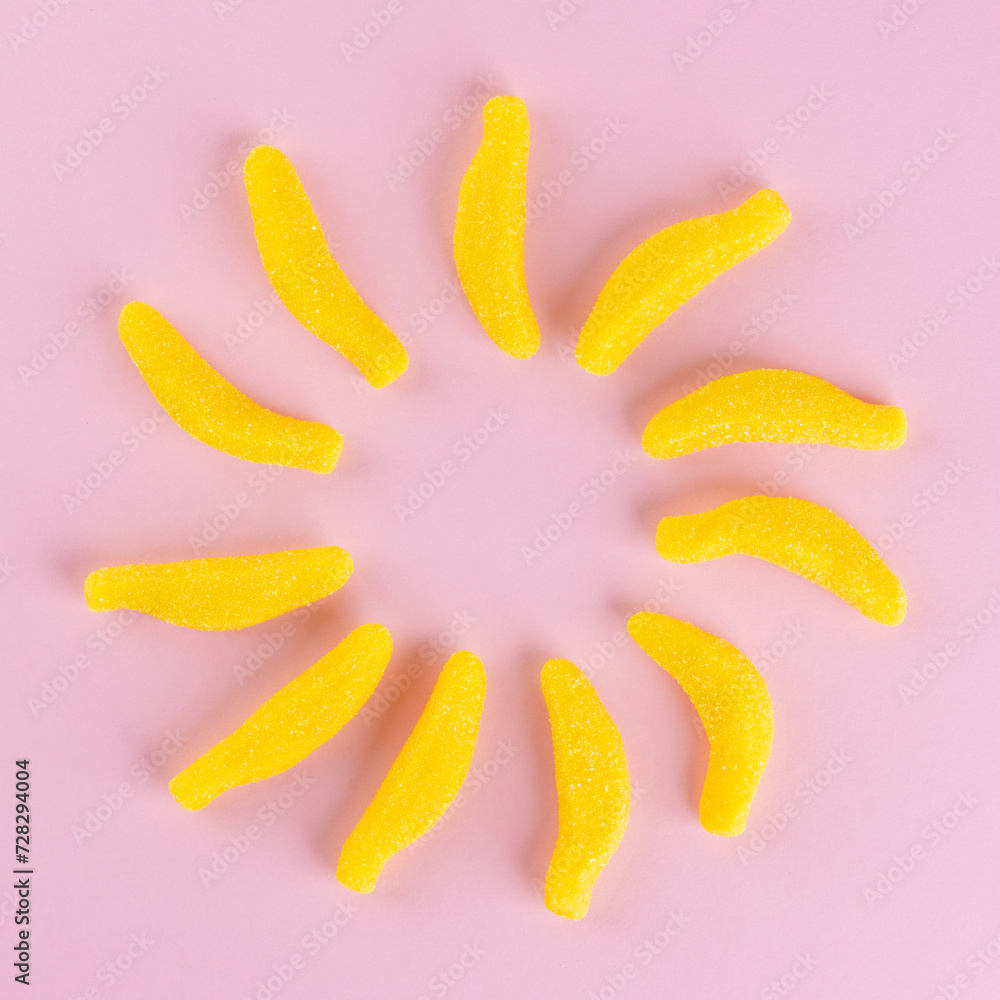 Swedish candy, chewy candies with banana flavor in the form of a sun on a pink background. Top view. Swedish candy, chewy candies with banana flavor in the form of a sun on a pink background. Top view.