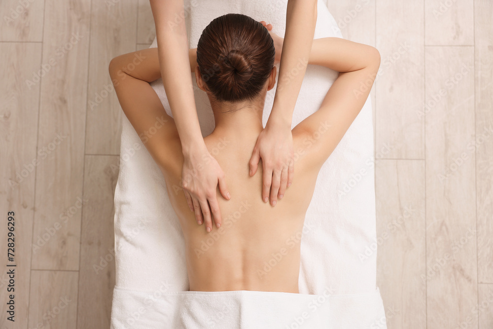 Woman receiving back massage on couch in spa salon, top view