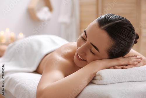 Beautiful woman relaxing on massage couch in spa salon, space for text