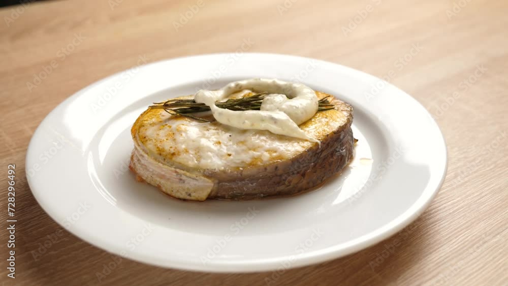 A freshly baked piece of salmon is placed on a plate and sauce is added A freshly baked piece of salmon is placed on a plate and sauce is added