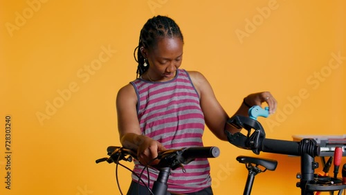 Atelier shop employee setting up bike repair stand before starting work on busted wheels, studio background. Professional securing bicycle on workstand before examining for damages, camera B photo