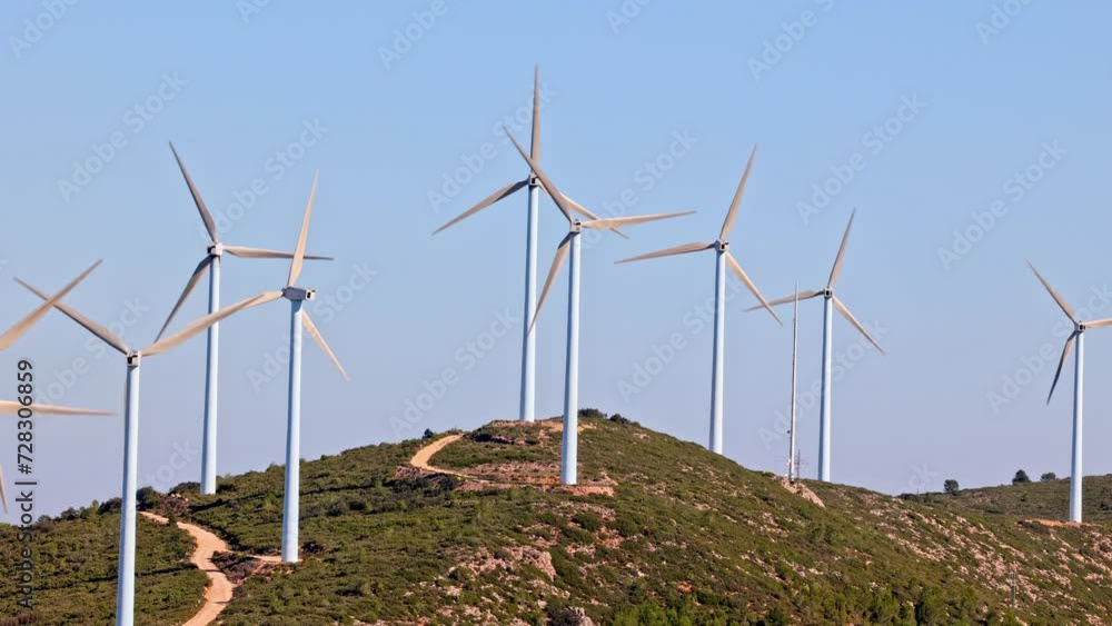 Wind turbines on beautiful sunny summer mountain landscape. Curvy road through mountain wind park. Green ecological power energy generation. Bunol wind farm, Spain. Wind turbines on beautiful sunny summer mountain landscape. Curvy road through mountain wind park. Green ecological power energy generation. Bunol wind farm, Spain.