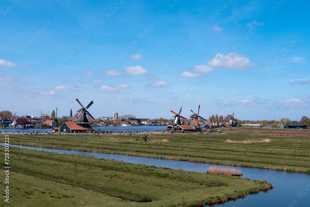 Welcome to Holland above a river and the windmills of Zaanse Schans, the Netherlands with its traditional houses, windmills, warehouses and workshops.