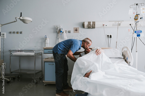 Man kissing woman lying on bed in hospital photo