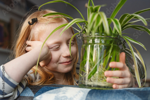 Smiling girl with spider plant at home photo
