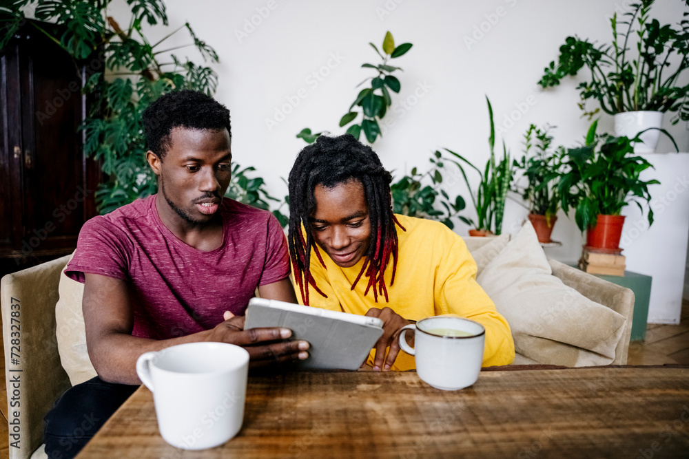 Man sharing tablet PC with friend at home Man sharing tablet PC with friend at home