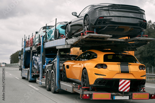 Car carrier trailer truck with brand new exotic luxury sport cars for a racing championship, car show or sale. Car transporter trailer loaded with italian car. Two-level modular hydraulic semi-trailer