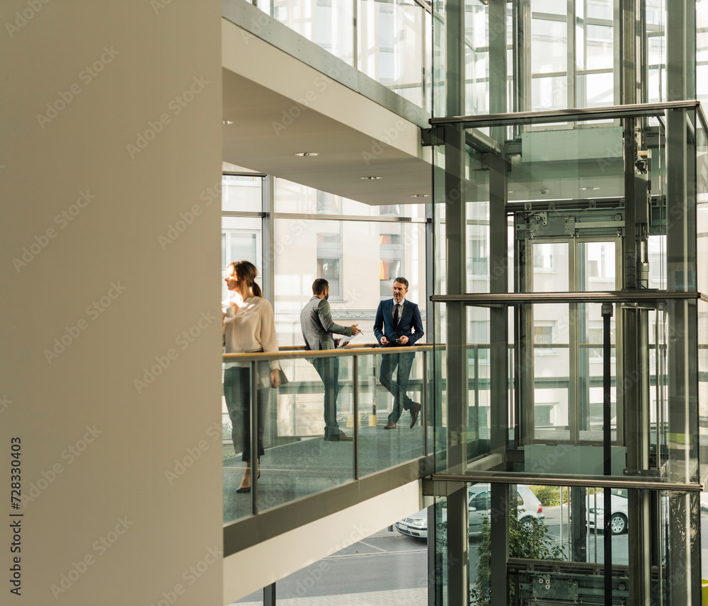 Coworkers talking on elevated walkway at office Coworkers talking on elevated walkway at office