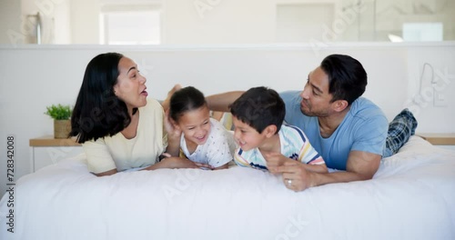 Happy family, bedroom and parents tickle children in home, bonding and laughing together. Bed, mother and father playing with kids for love, relax and smile for funny game in the morning at house photo