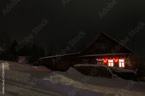 View from a hill on wooden houses covered snow at night. Scenery of ski resort with lights. Theme of travel.