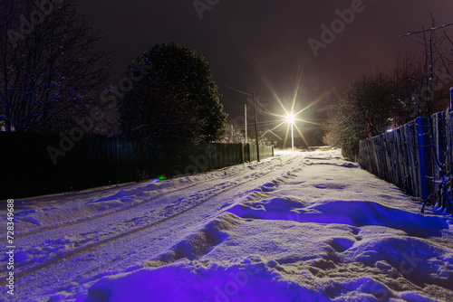Road covered snow with lanterns in the north village. Rural view in winter.