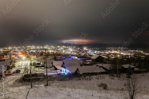 View from a hill on wooden houses covered snow. Scenery of ski resort with lights. Theme of travel.