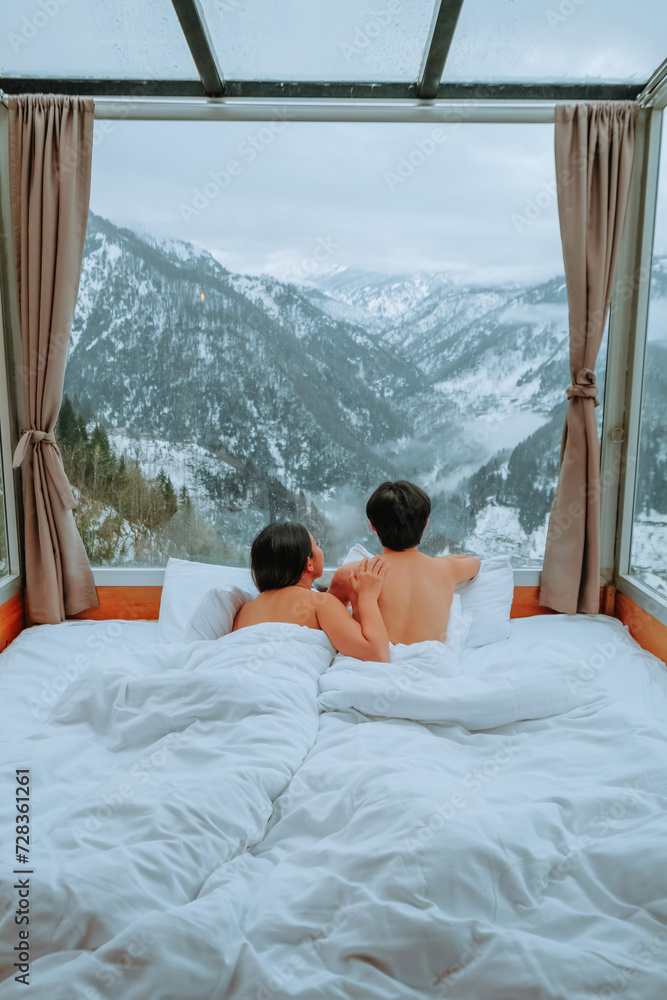 A couple enjoys a beautiful morning view of snow in a glass room at their winter home in Georgia. A couple enjoys a beautiful morning view of snow in a glass room at their winter home in Georgia.