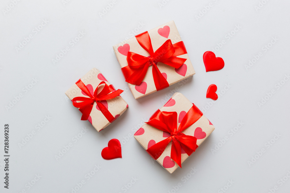 Top view photo of valentine day decorations gift box with red ribbon bow on colored background. Holiday gift boxes with top view Top view photo of valentine day decorations gift box with red ribbon bow on colored background. Holiday gift boxes with top view